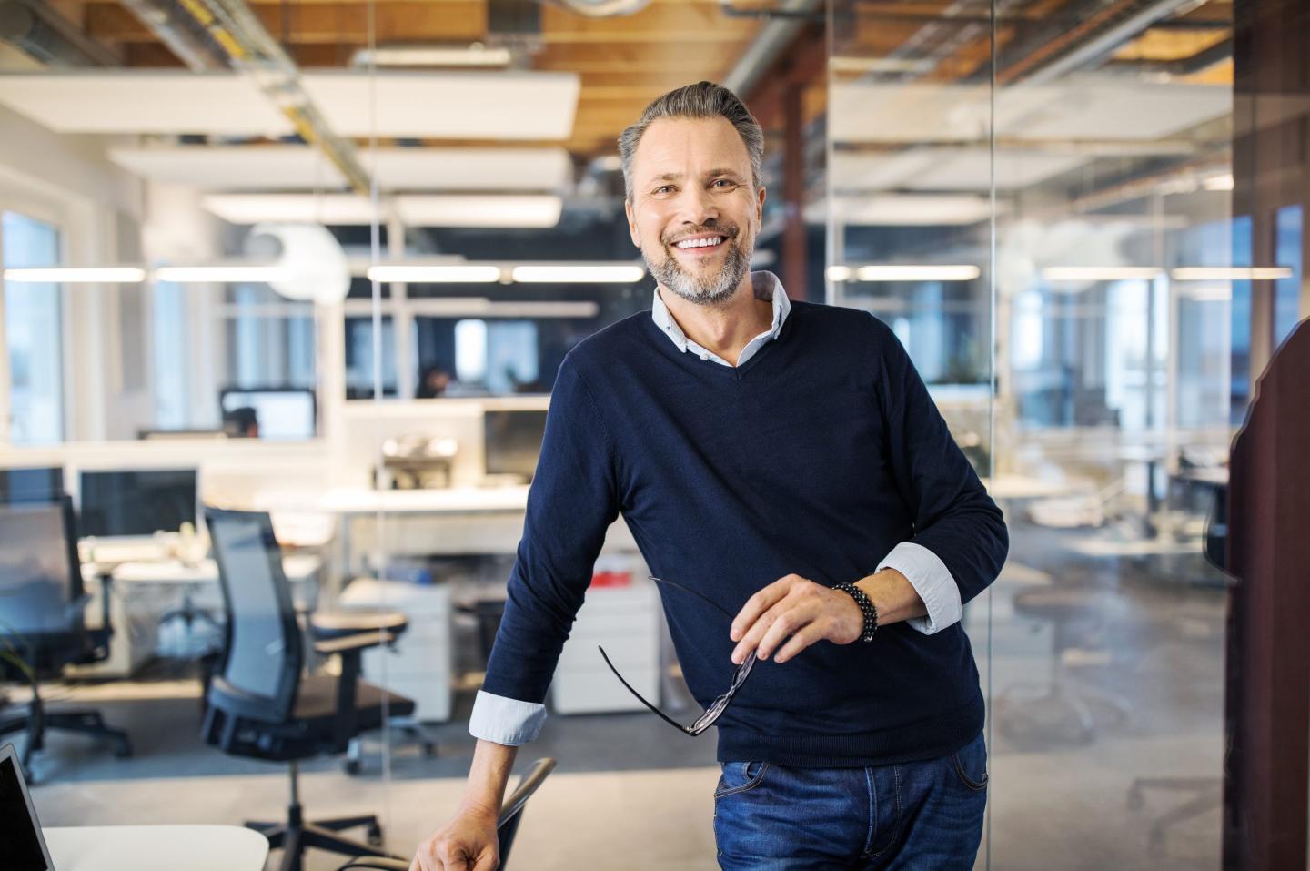 Portrait of successful mid adult businessman standing in office.