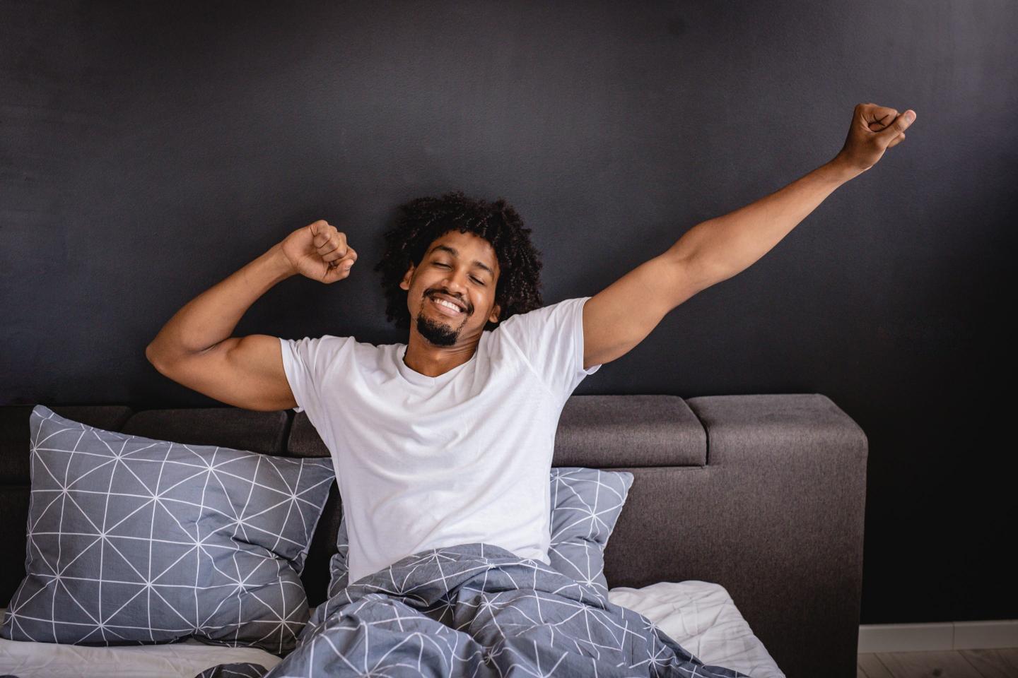 man is waking up in bed in the morning with a smile on his face