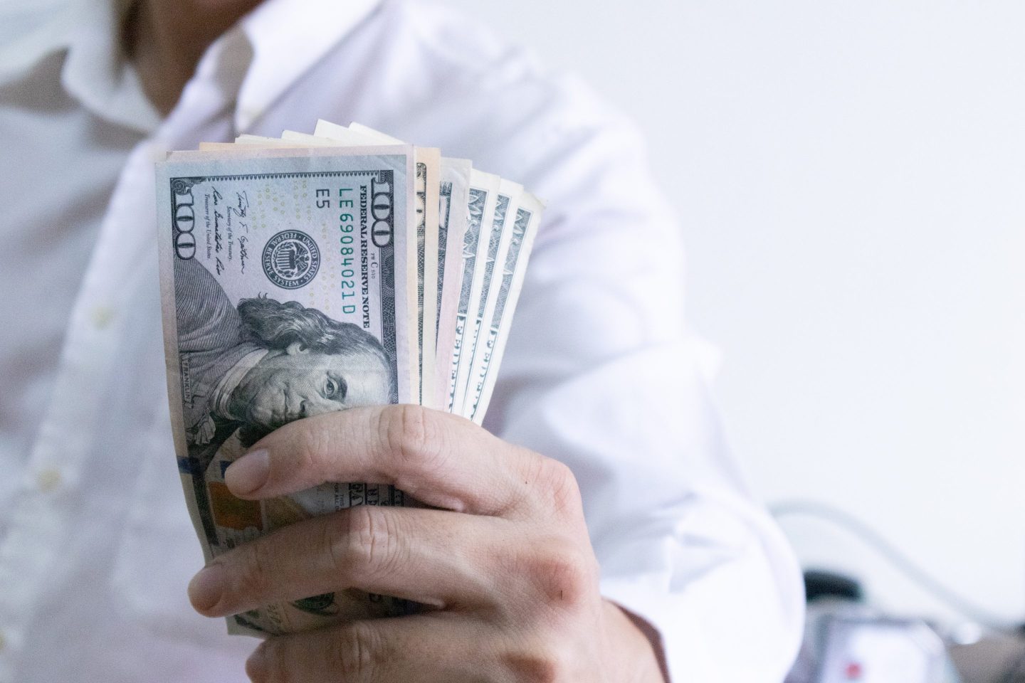 Picture of a person holding U.S. dollar bills.