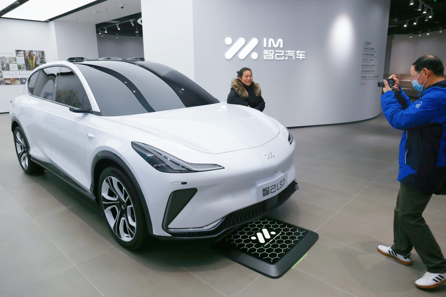 A woman poses for photos with a concept car at an auto dealership in Shanghai.