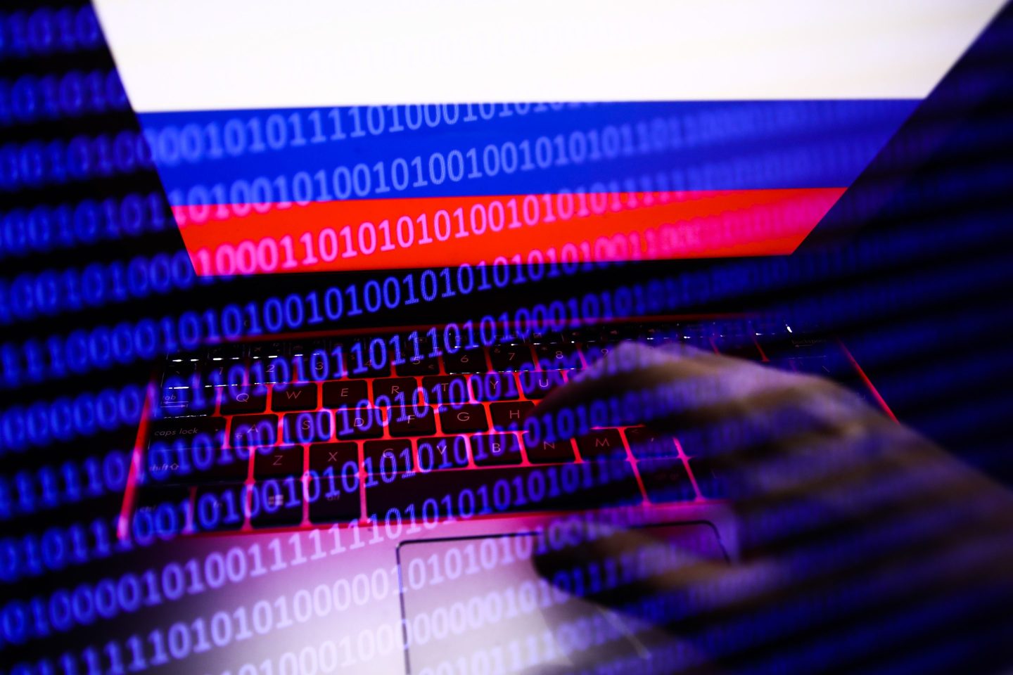 Russian flag displayed on a laptop screen and binary code code displayed on a screen are seen in this multiple exposure illustration photo taken in Krakow, Poland on February 16, 2022.