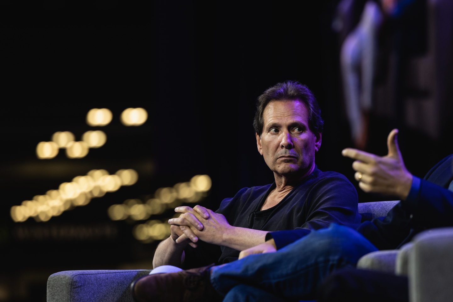 Dan Schulman listens to other speaker on stage at conference.