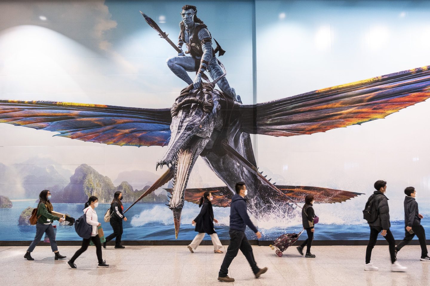 Commuters walk past a large commercial advertisement banner promoting the movie Avatar: The Way of Water (Avatar 2), produced by Lightstorm Entertainment and distributed by 20th Century Studios, in Hong Kong.