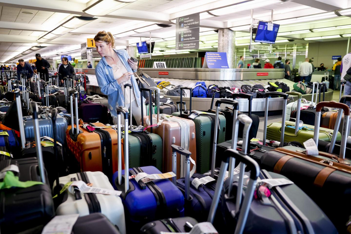 Exhausted passengers look through piles of suitcases in an airport