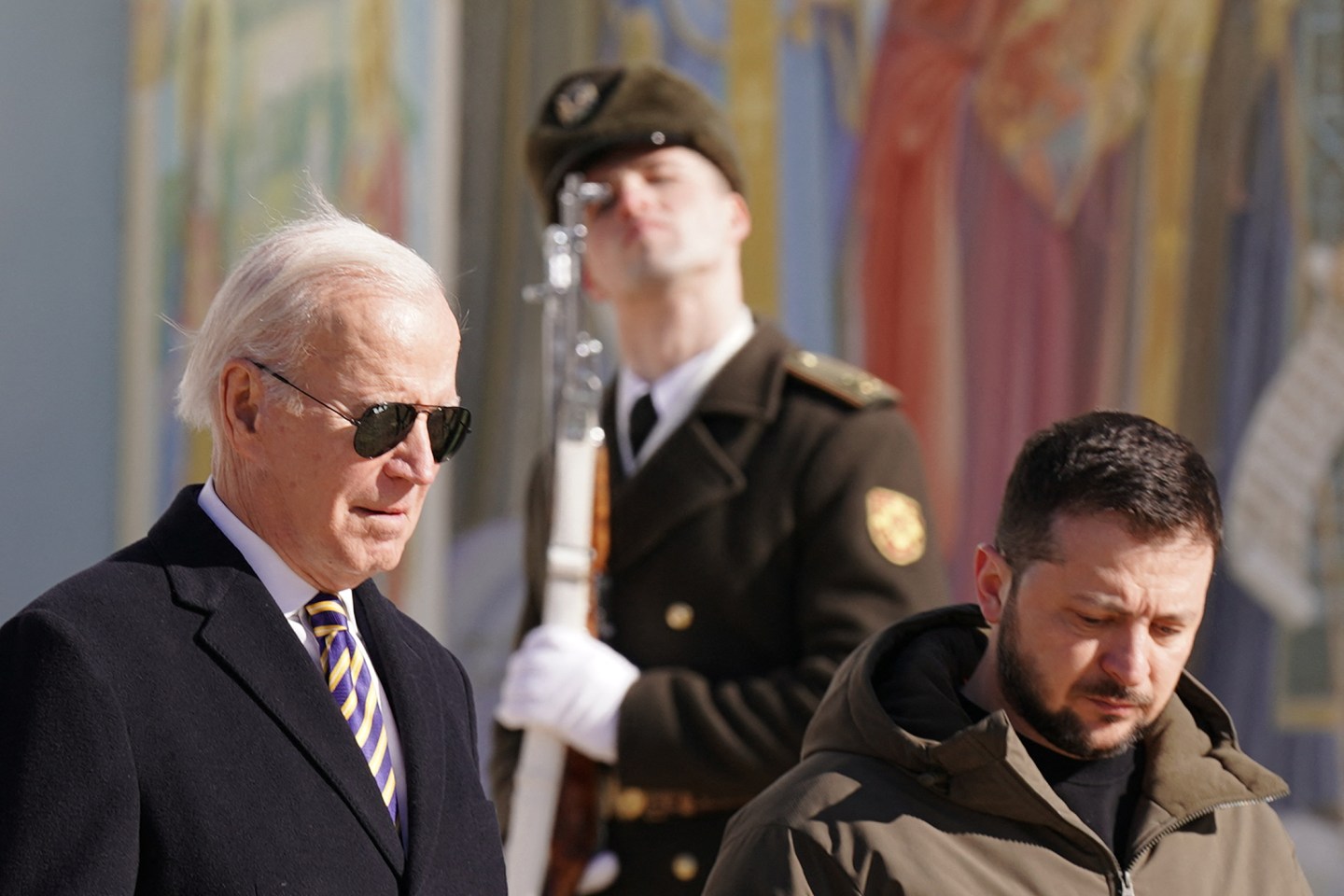 US President Joe Biden (L) walks next to Ukrainian President Volodymyr Zelensky (R) past a religious mural at the St. Michaels Golden-Domed Cathedral, as he arrives for a visit in Kyiv on Feb. 20, 2023.