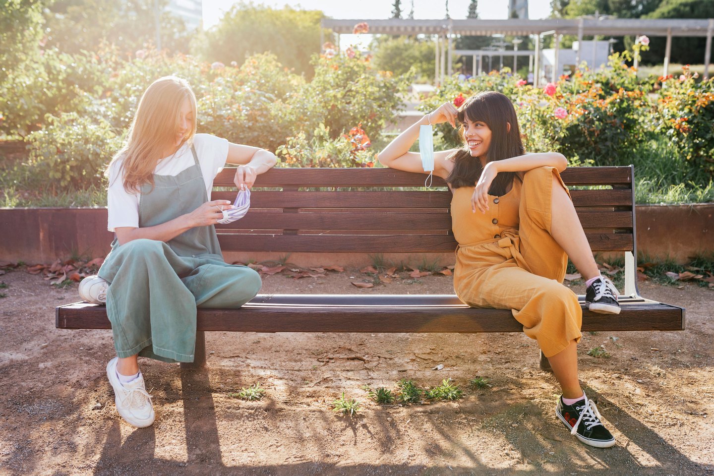 Two friends sitting in a park keeping a safe distance from each other