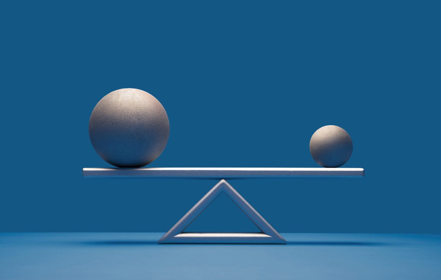 A large ball and a small ball balance one another on a scale.