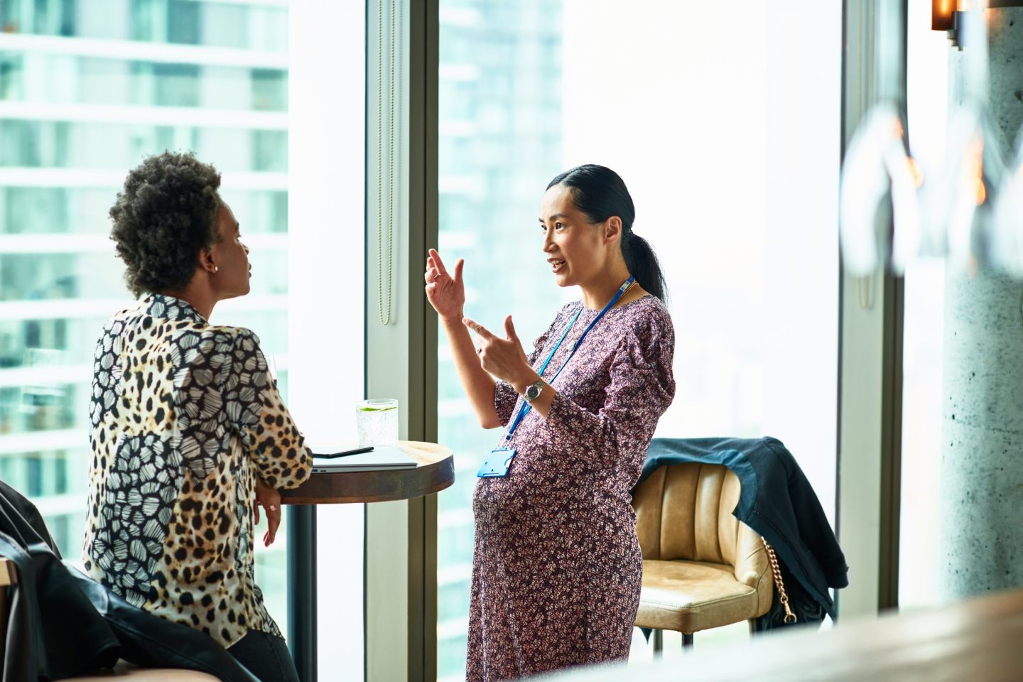 Pregnant Chinese woman gesturing and explaining to colleague
