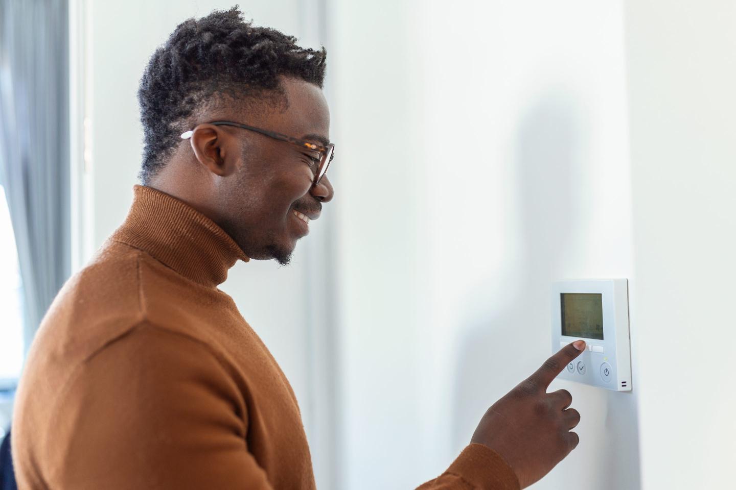 Man using thermostat while wearing sweater