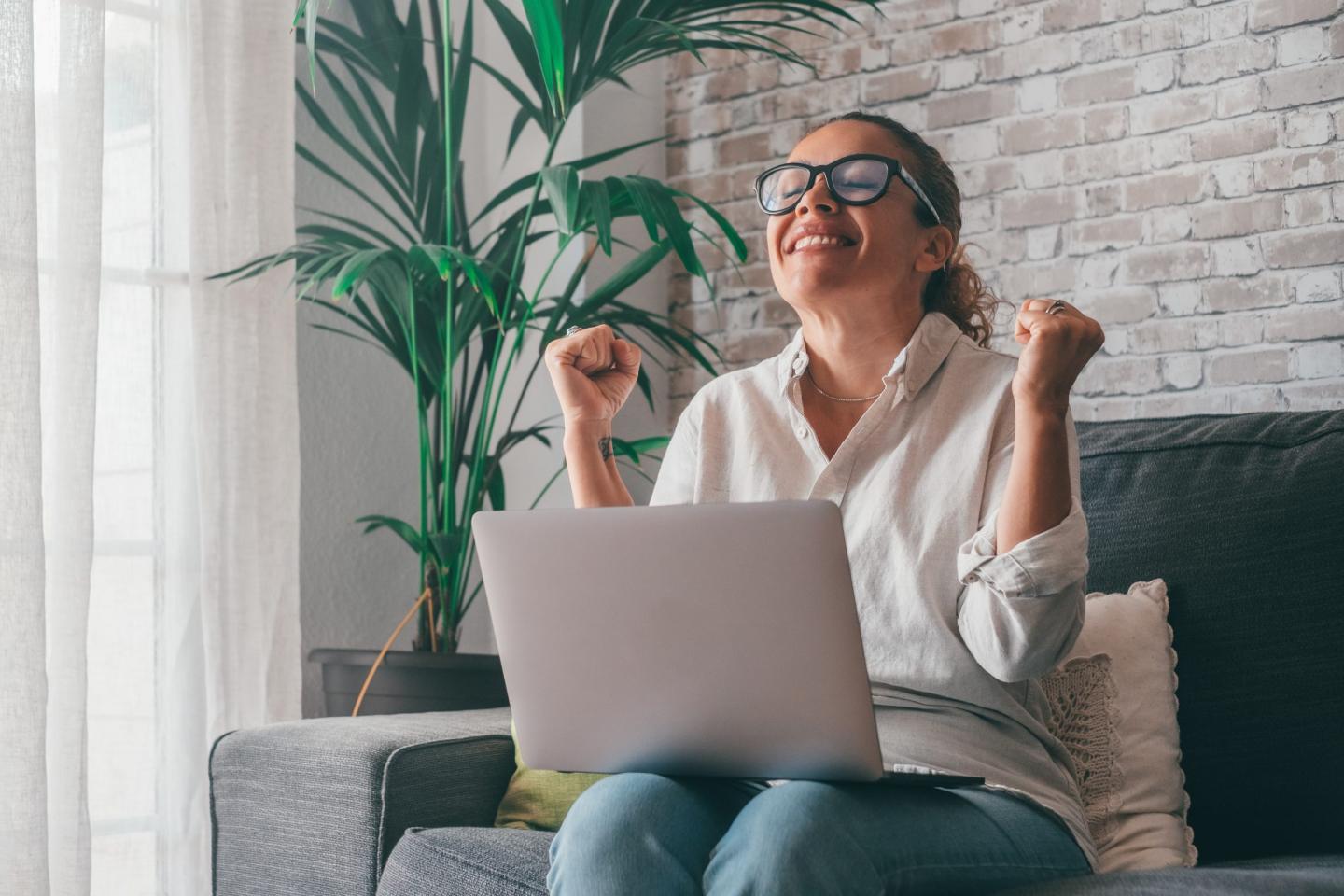 Young Woman Using Laptop While Sitting On Sofa At Home