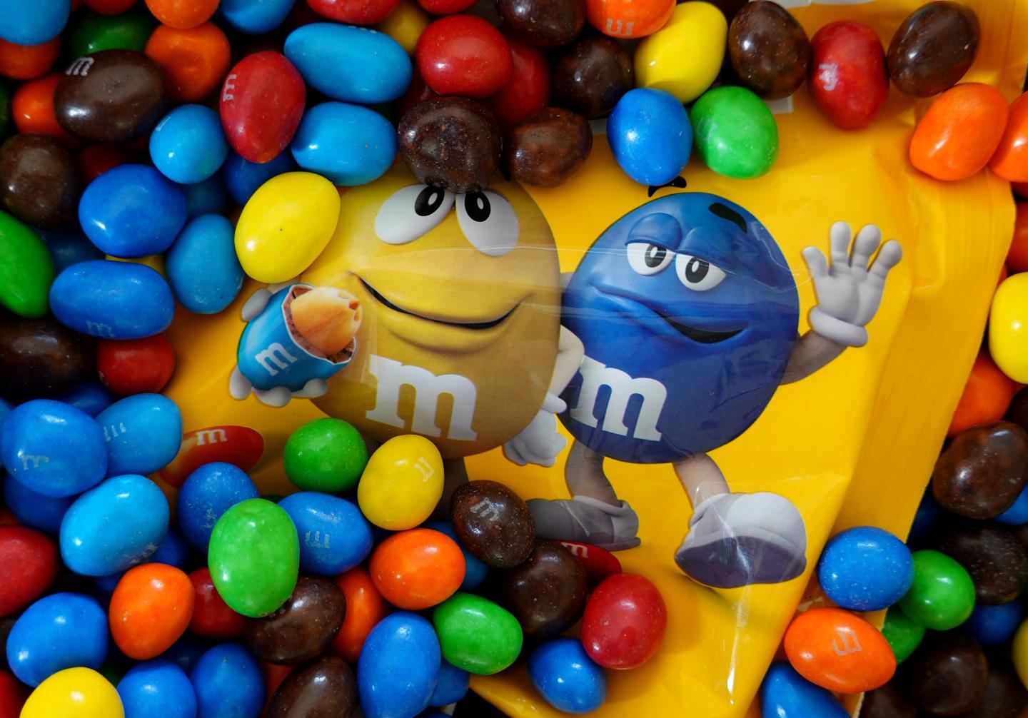 A packet of peanut M&M's seen almost completely buried in the candies.
