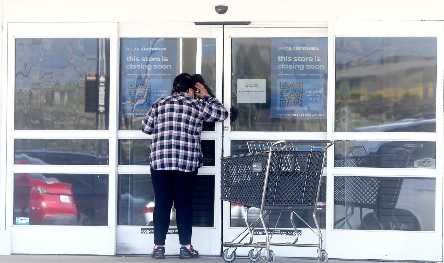 A customer looks into a closed Bed Bath and Beyond store