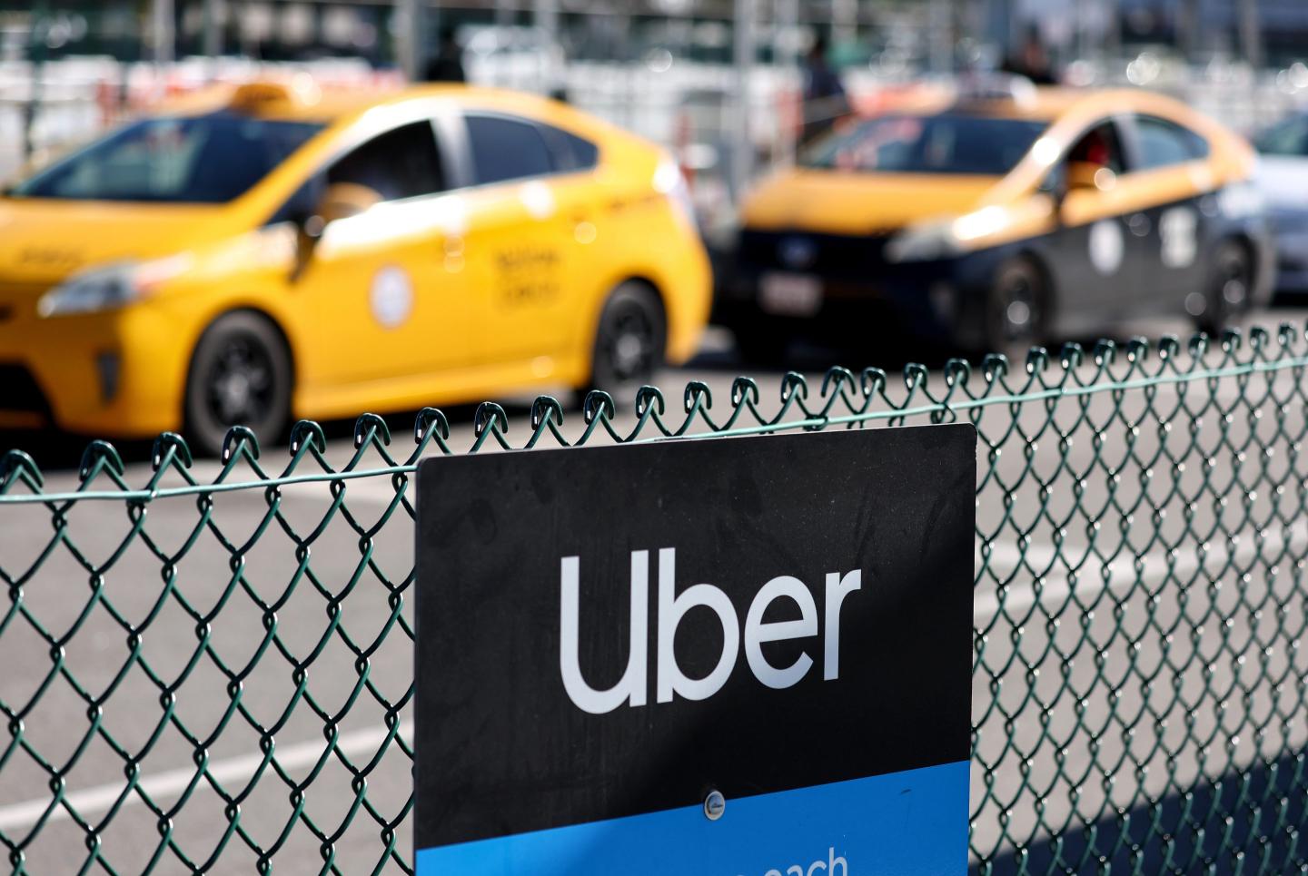 An Uber rideshare sign is posted nearby as taxis wait to pick up passengers at Los Angeles International Airport