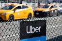 An Uber rideshare sign is posted nearby as taxis wait to pick up passengers at Los Angeles International Airport