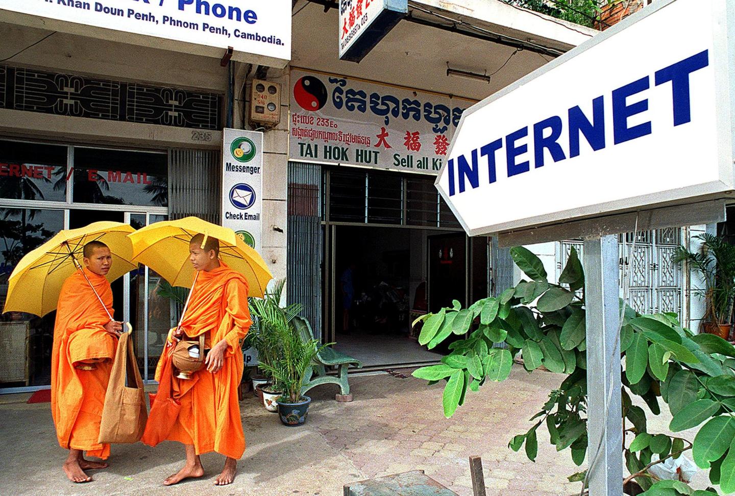 Cambodian monks stand in front of an internet cafe in 2000. In 2022, Cambodia is preparing to power up its its new National Internet Gateway, which will funnel all web traffic through a state-controlled entry point.