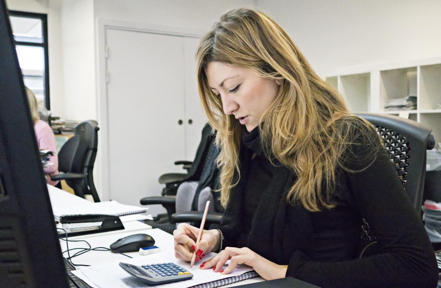Woman writing notes at desk.