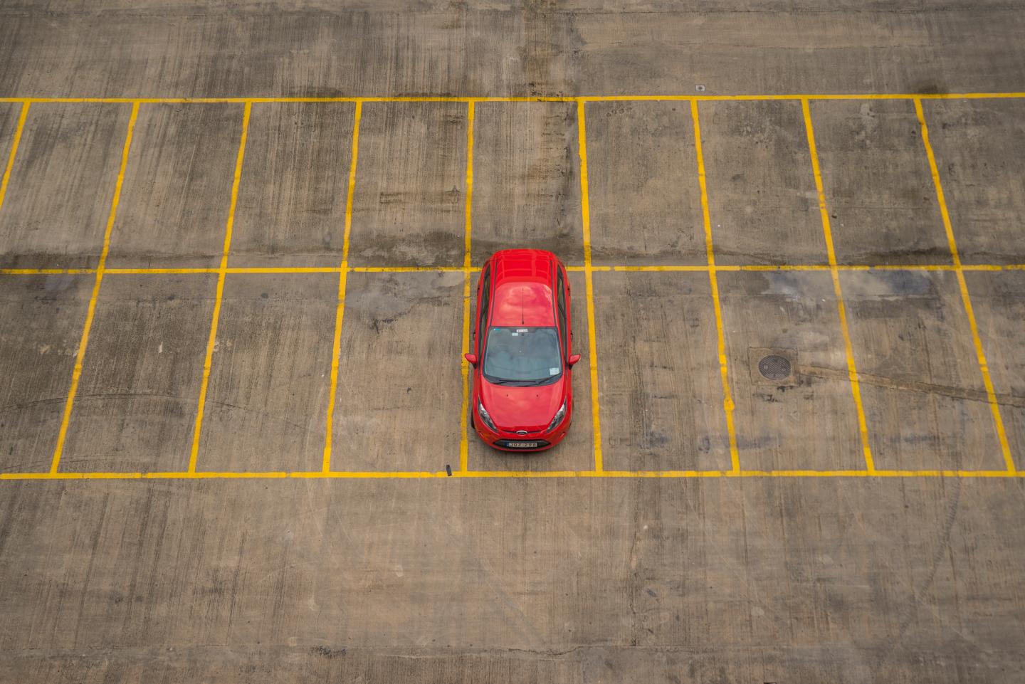 A red car in an empty parking lot.