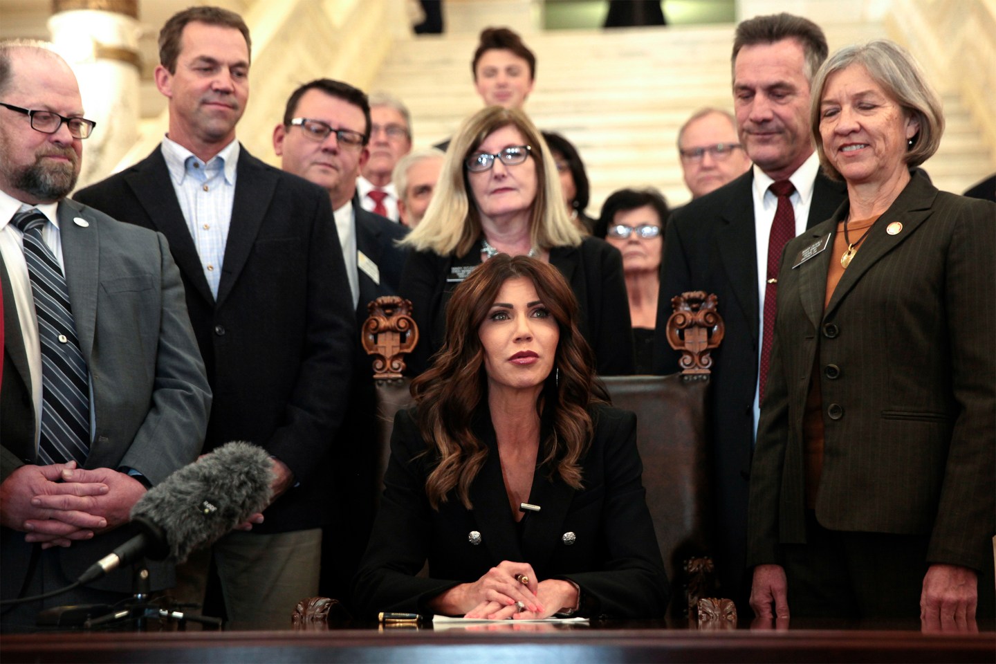 South Dakota Gov. Kristi Noem signs a bill on Feb. 3, 2022, at the state Capitol in Pierre, S.D., that will ban transgender women and girls from playing in school sports leagues that match their gender identity.
