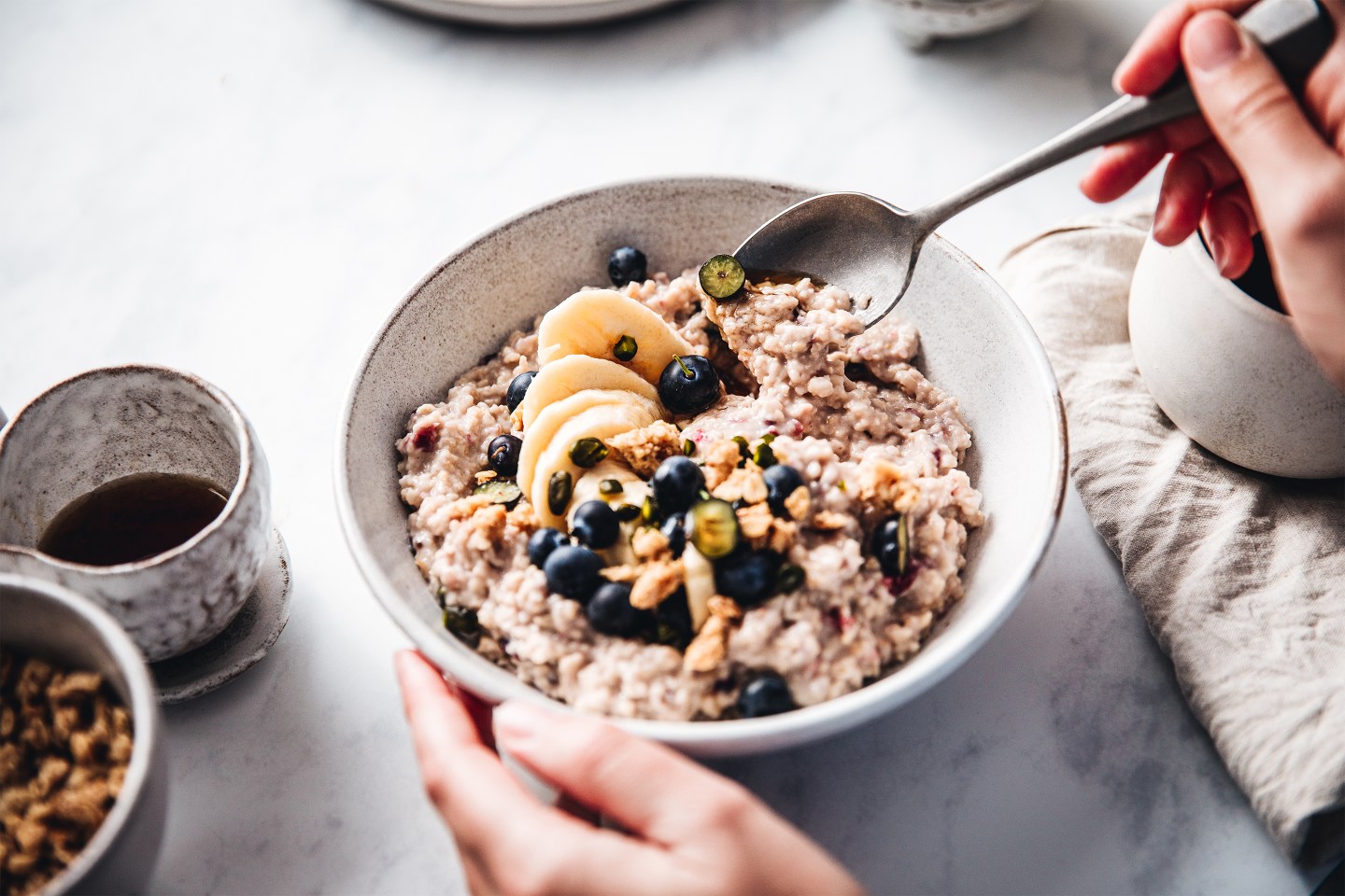 Female making healthy oatmeal breakfast in kitchen.