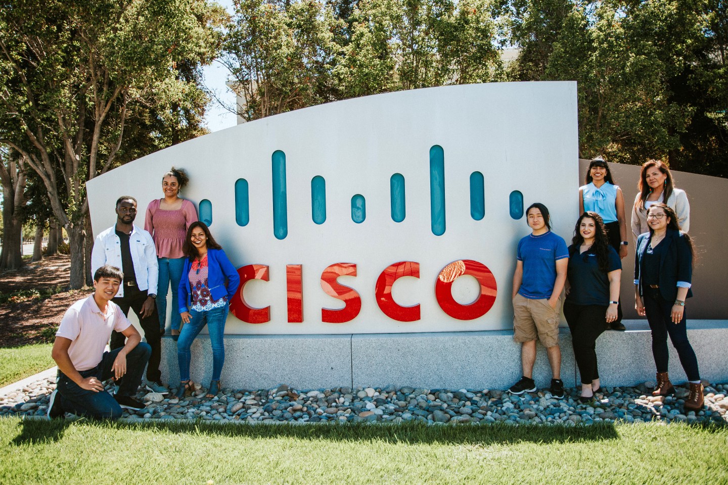 A group of people standing in front of a Cisco sign.