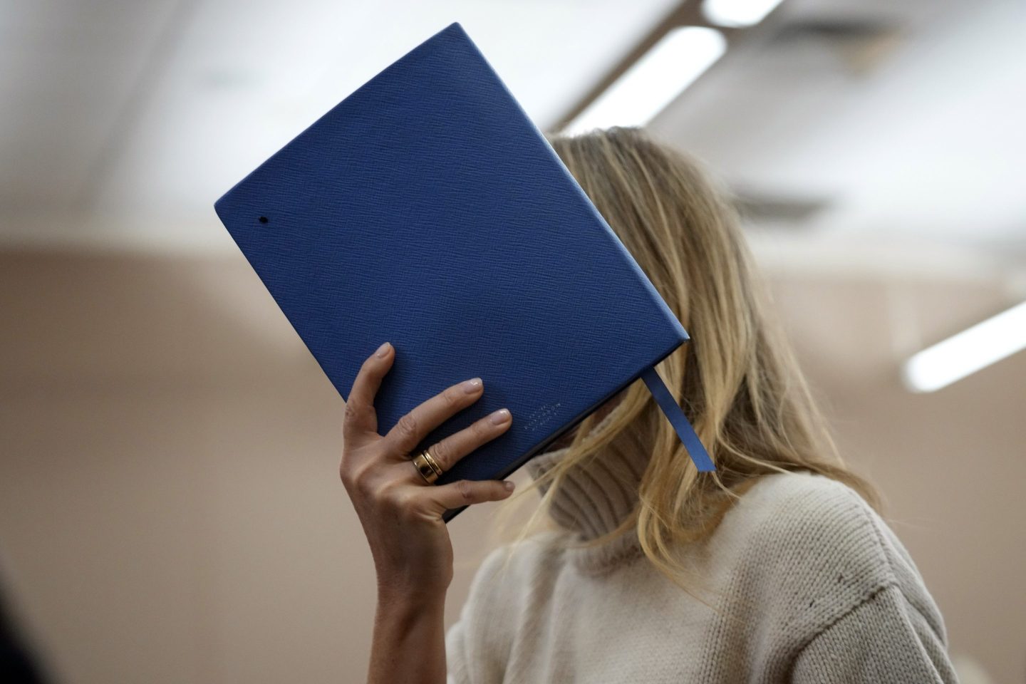 Actor Gwyneth Paltrow shields her face with a blue notebook as she exits a courtroom on March 21, 2023, in Park City, Utah, where she is accused in a lawsuit of crashing into a skier during a 2016 family ski vacation, leaving him with brain damage and four broken ribs.