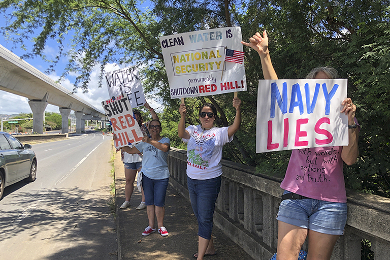 Protestors upset with the Department of Defense's response to the leak of jet fuel into the water supply hold signs outside the gate at Joint Base Pearl Harbor-Hickam, Hawaii, Friday, Sept. 30, 2022.