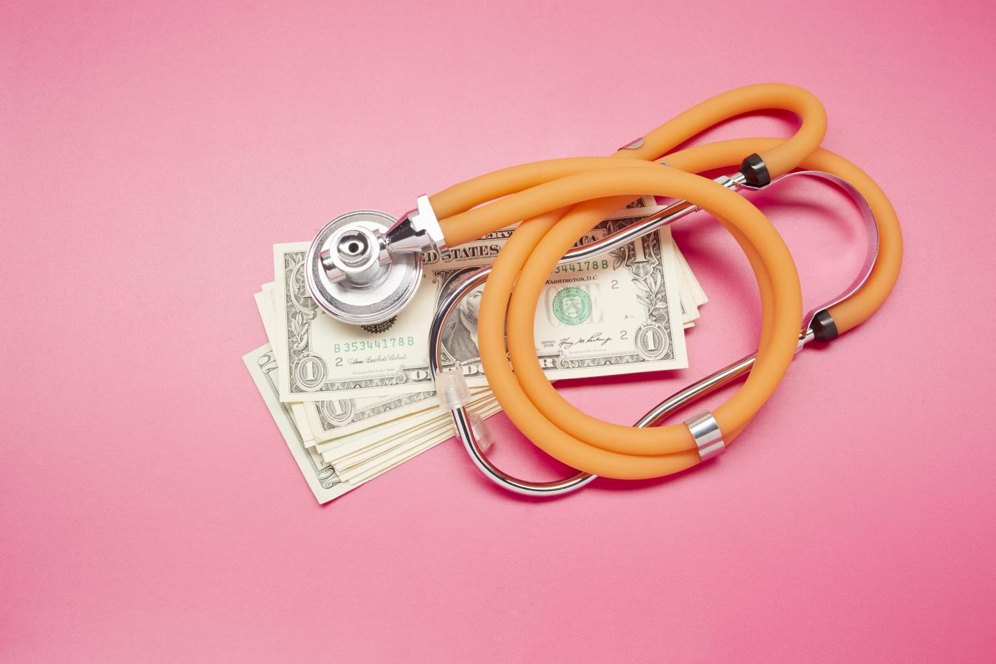 High angle view of stethoscope and American Dollar banknotes on colored background