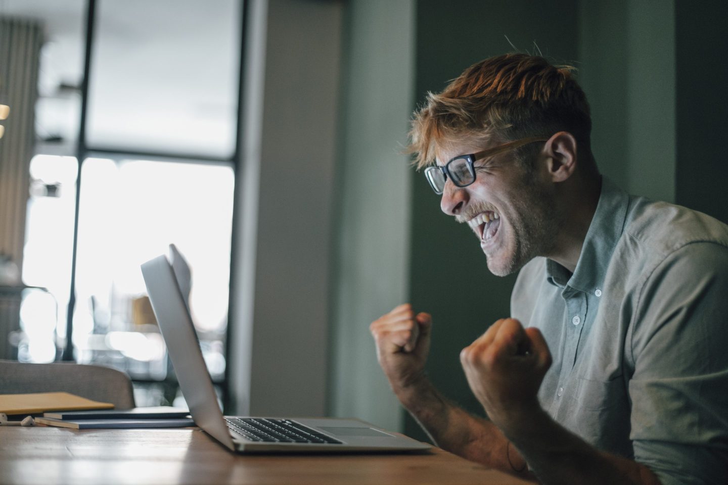 A man cheers while looking at a laptop screen