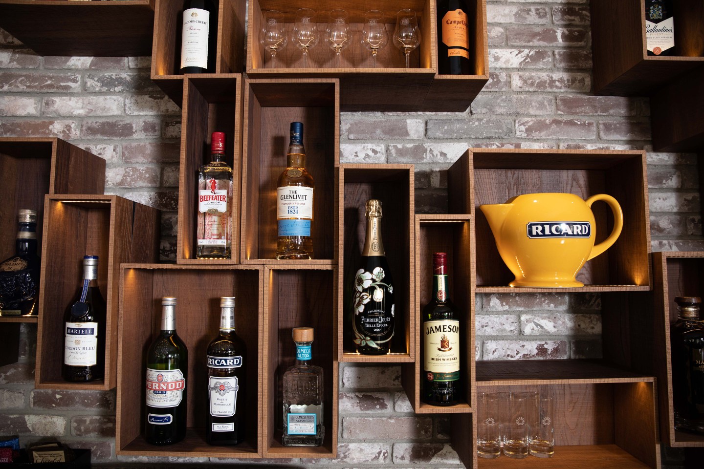 Bottles of alcoholic beverages, produced by Pernod Ricard SA, sit in display cases behind the bar at the company's headquarters in Paris, France.