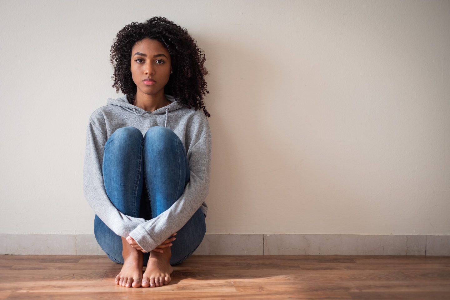 Photo of a young woman sitting by herself looking sad