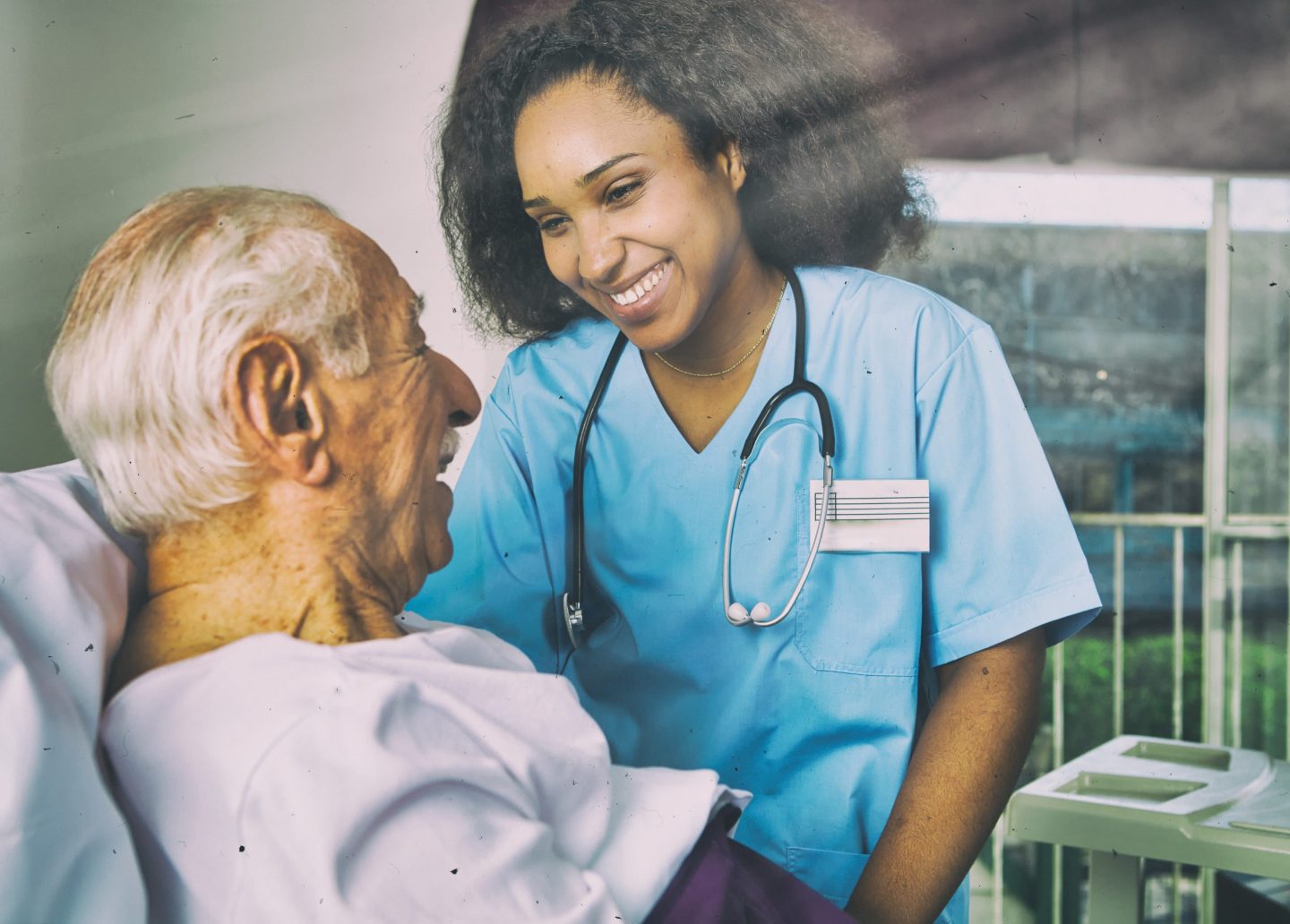 A nurse assisting an elderly patient as both smile