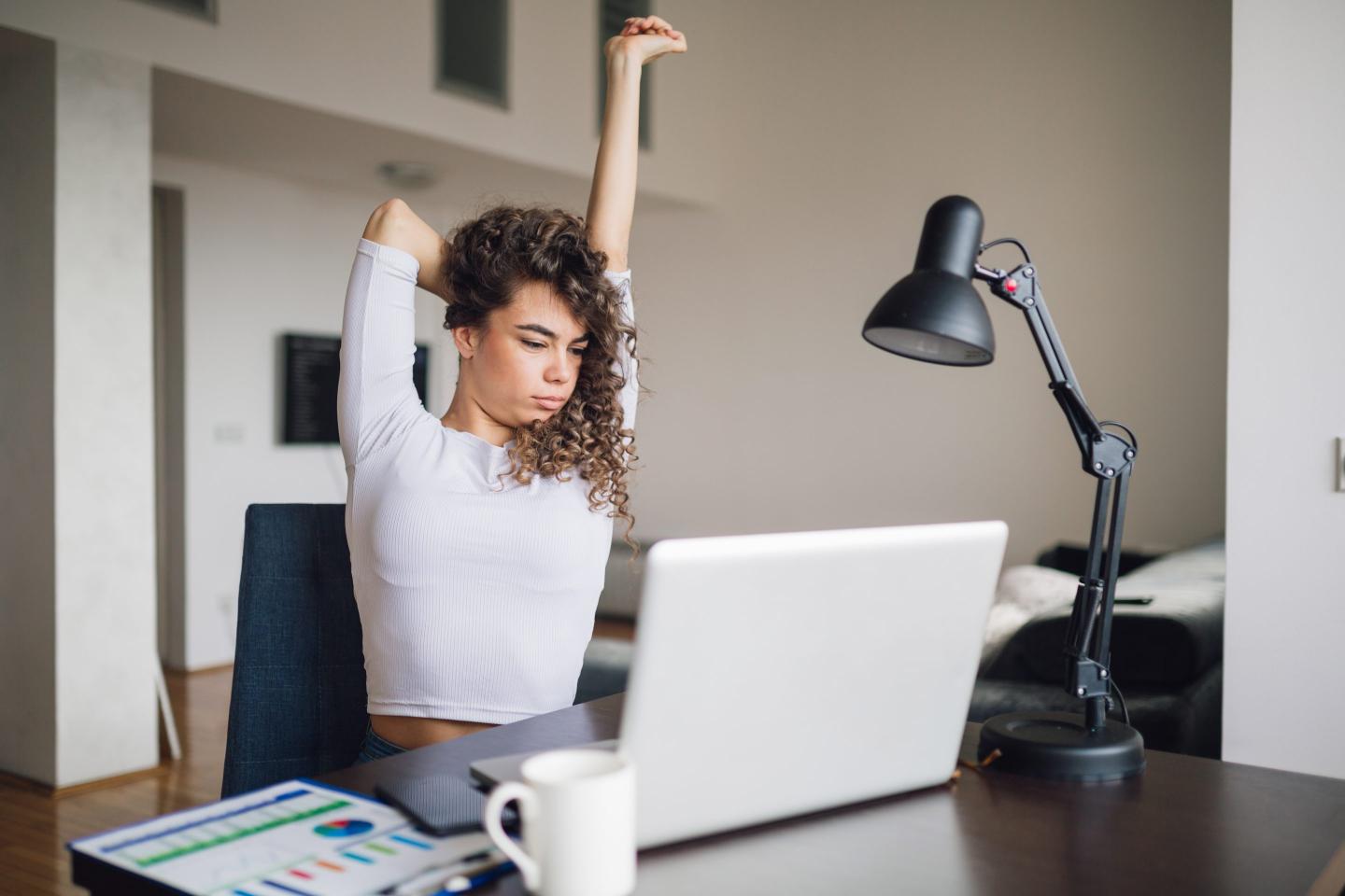 Businesswoman stretching at home desk