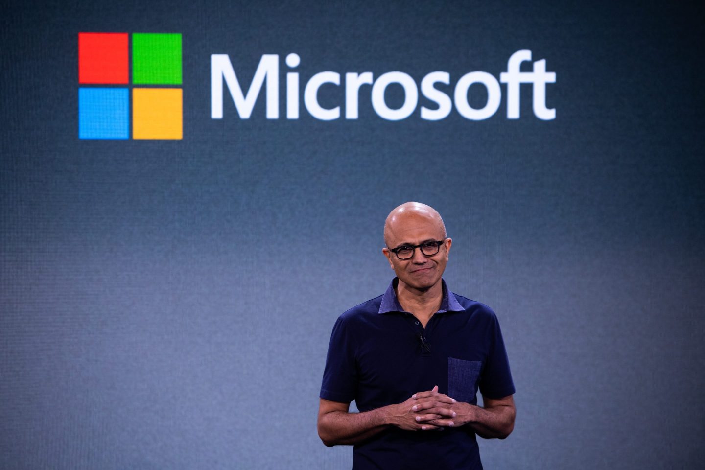 Satya Nadella, CEO of Microsoft in front of the company's logo