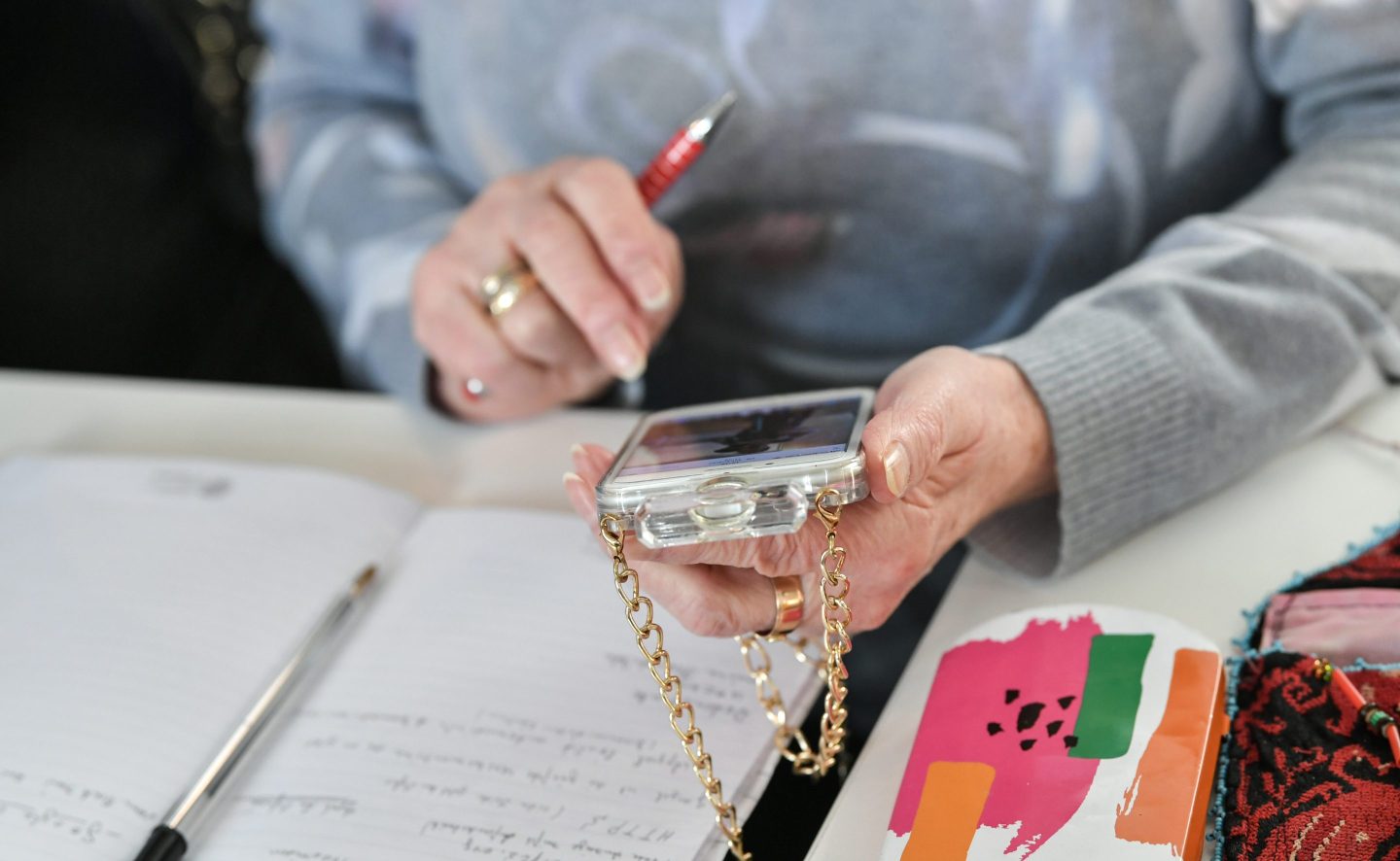 A senior citizen is holding her smartphone.