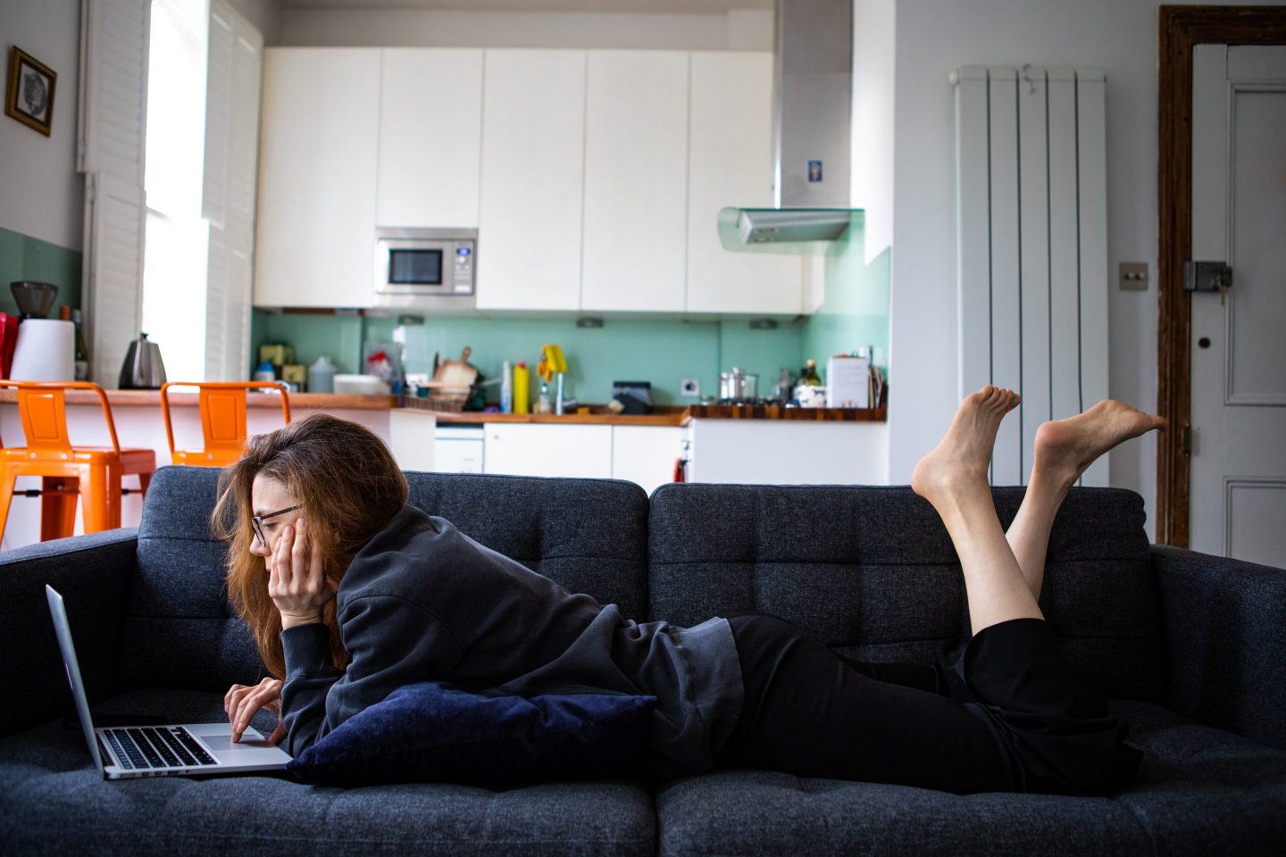A woman on her sofa working remotely