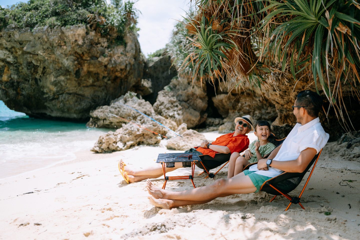 Grandfather, father and young daughter enjoying a secluded beach campsite, Okinawa, Japan