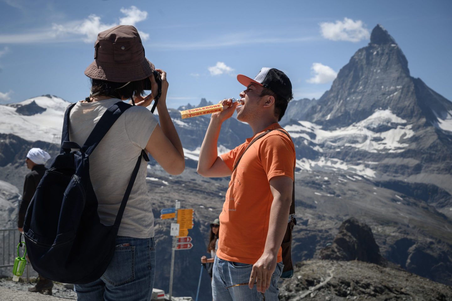 Tourist posing with the Matterhorn mountain and a bar of Toblerone.