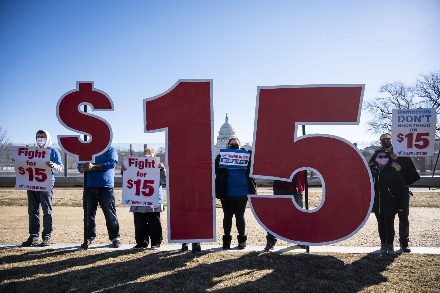 Activists with Our Revolution hold $15 minimum wage signs outside the Capitol complex on Thursday, Feb. 25, 2021.