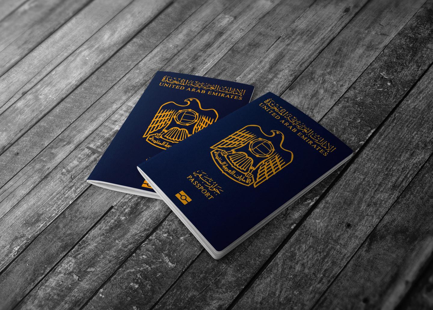 Two UAE passports on a wooden surface.