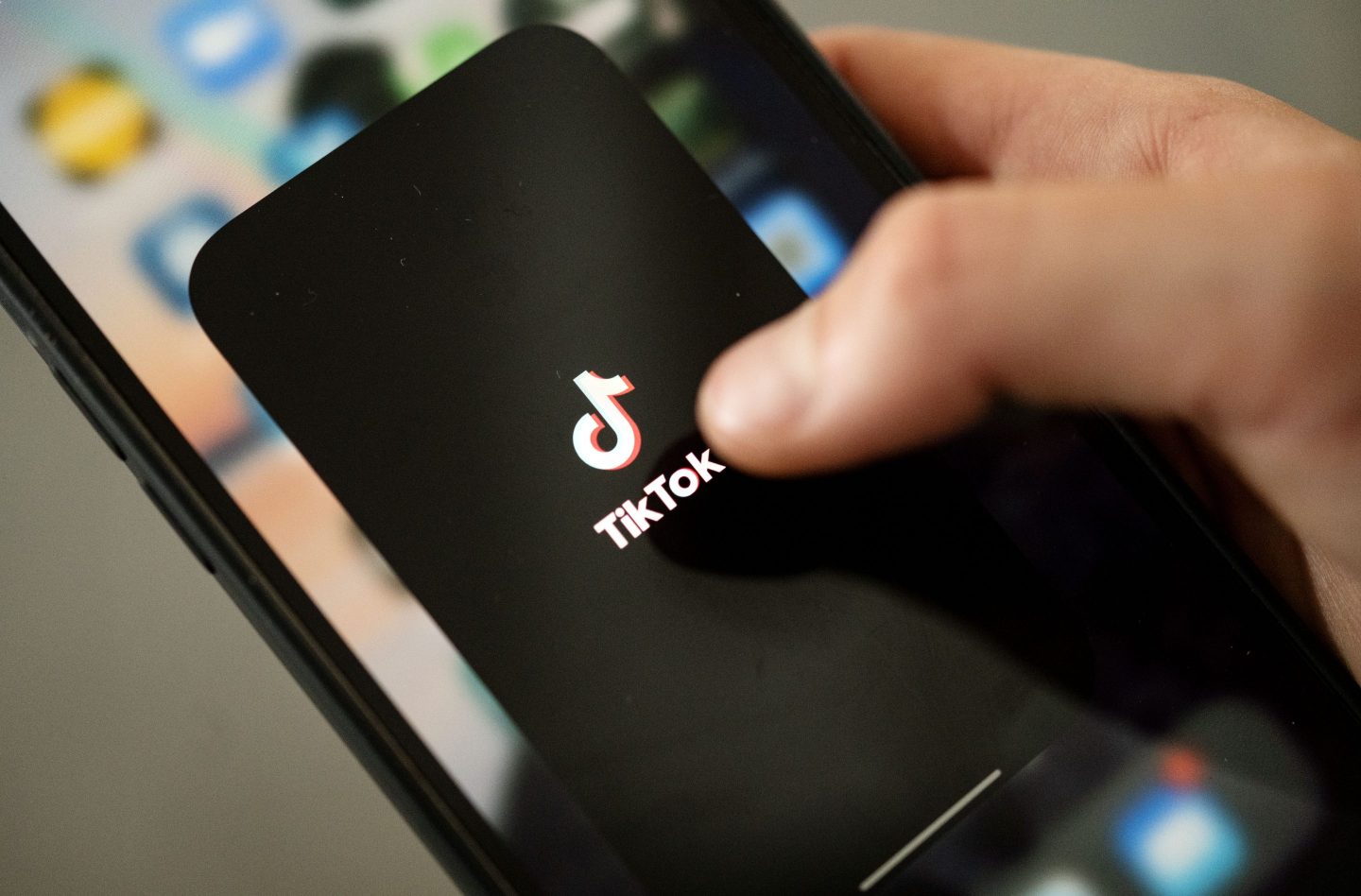 A teenager taps the TikTok logo on a smartphone.