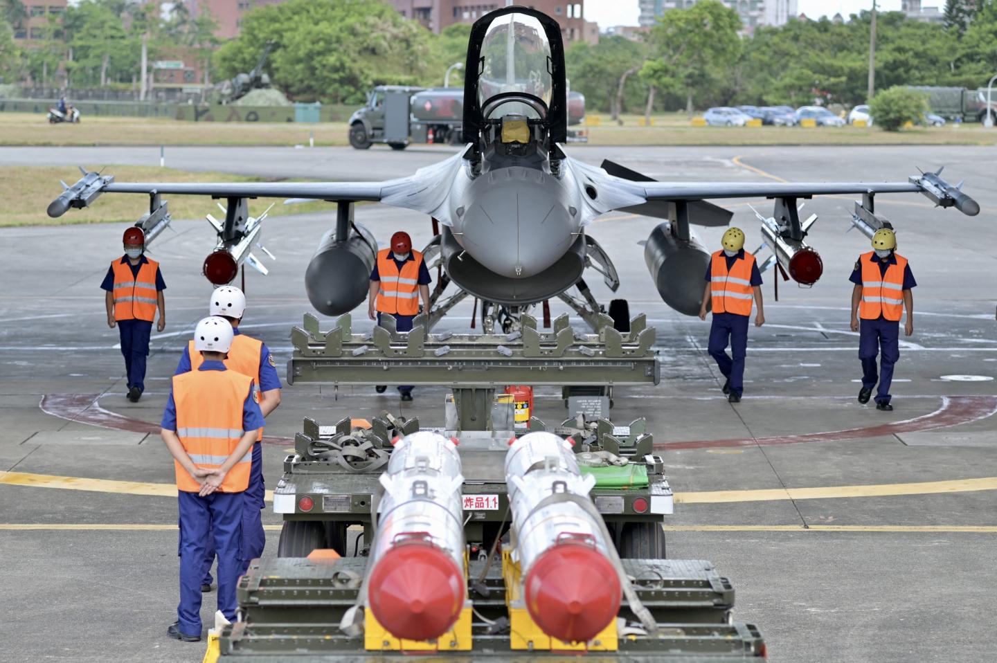 Air Force soldiers clear the ground in front of an armed F-16V fighter jet