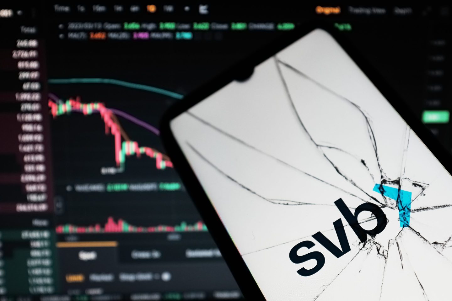 A phone with a cracked screen showing "SVB" and a downward trending stock chart