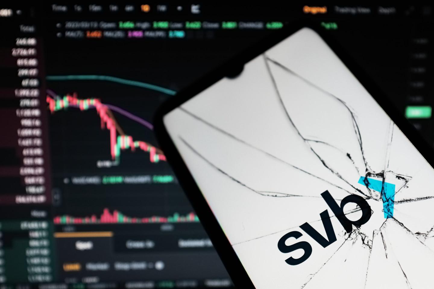 A phone with a cracked screen showing "SVB" and a downward trending stock chart