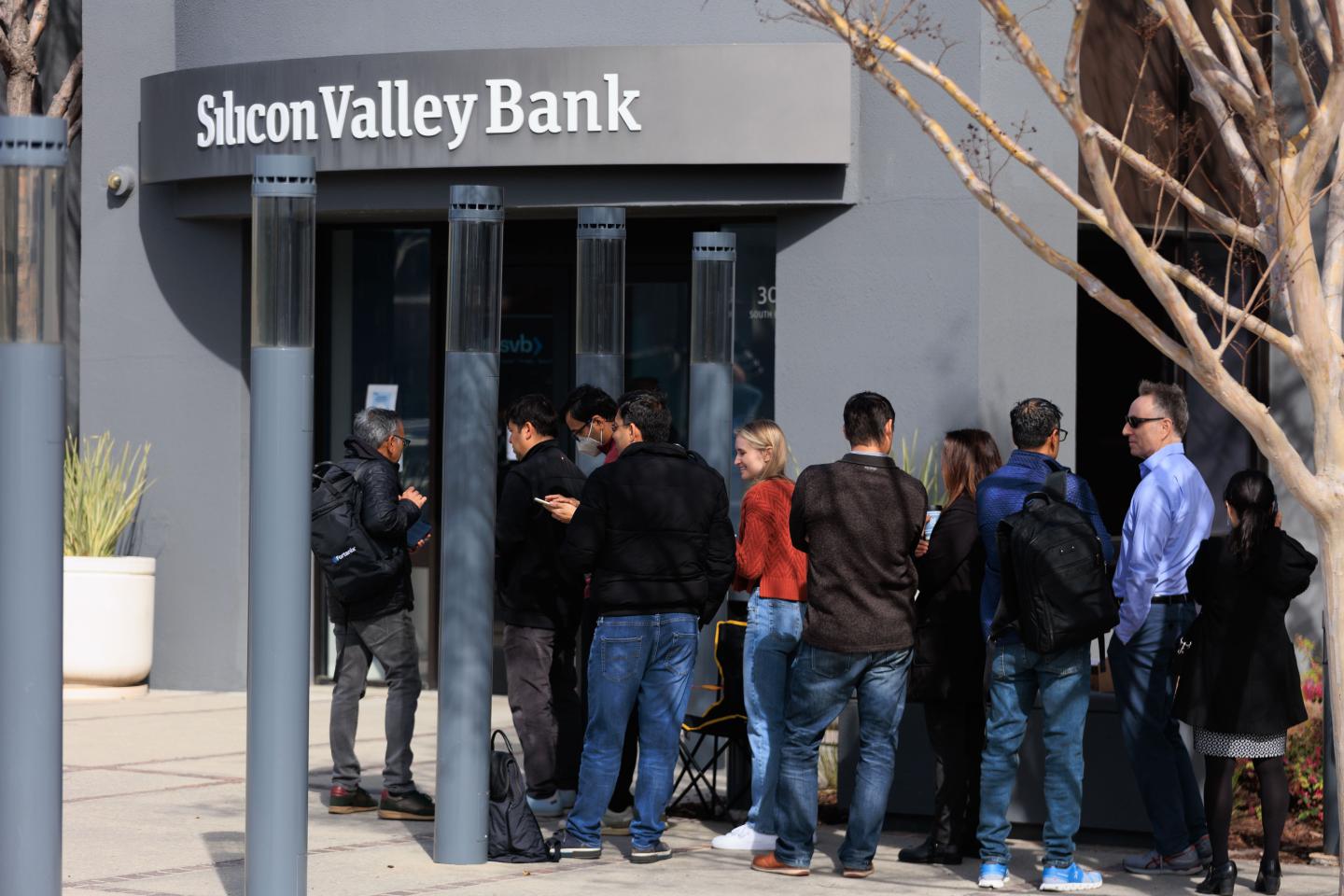People wait outside the Silicon Valley Bank headquarters in Santa Clara, Calif., to withdraw funds.