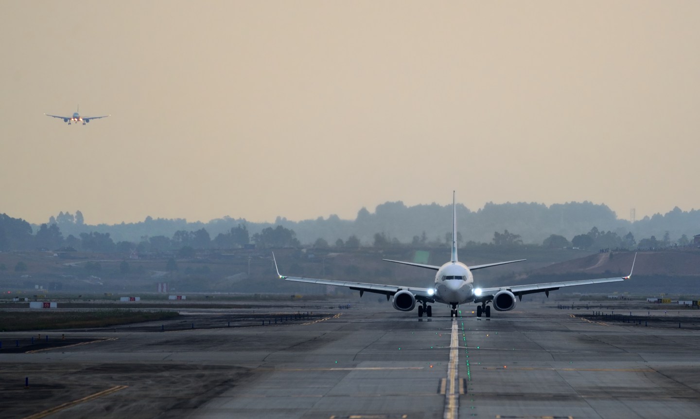 A plane lands on a runway in low light