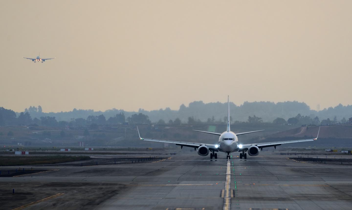 A plane lands on a runway in low light