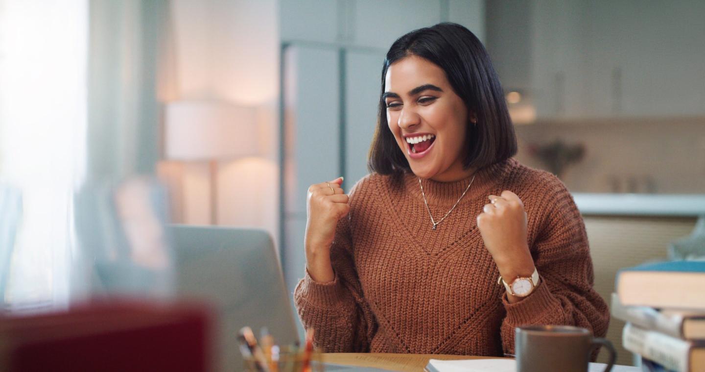 Woman fist pumping in front of laptop