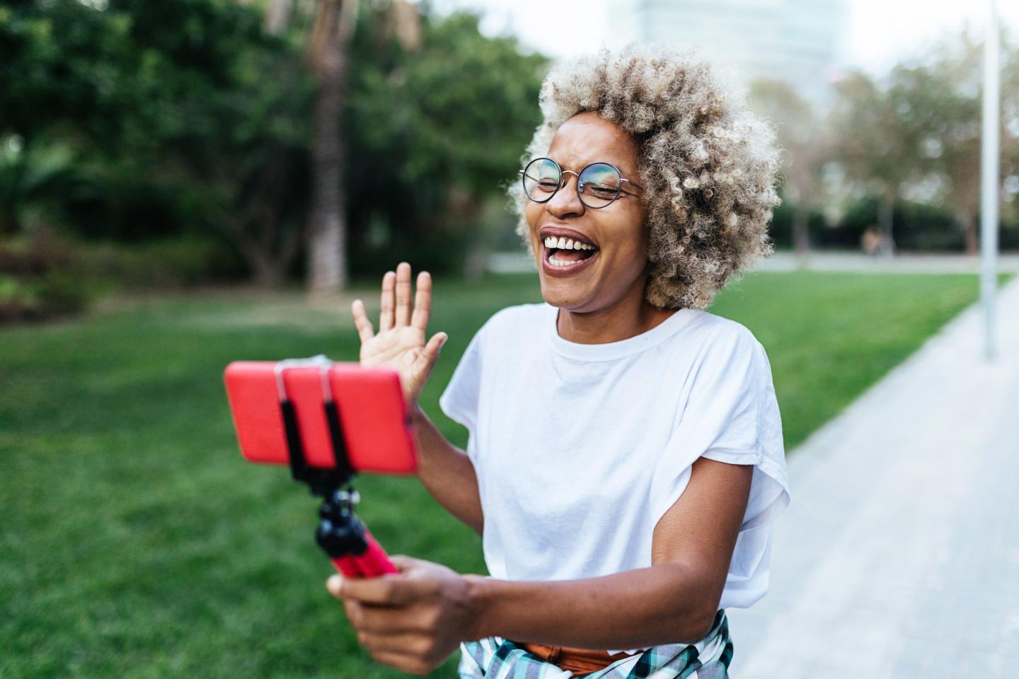 African-American vlogger recording content for her social networks with a mobile phone in city park.
