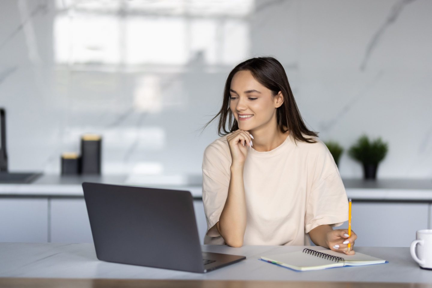 Happy young woman using laptop in cook room