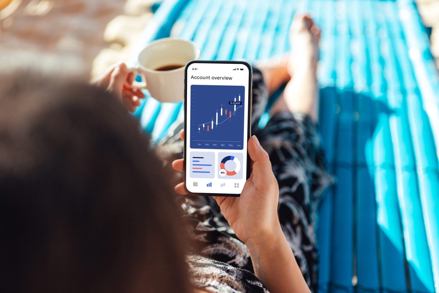 Woman sitting in chair drinking coffee and checking her investment balances